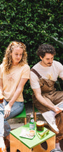 Man with a cream t shirt with a banana and sunglasses in buen dia coffee and a woman wearing a yellow t shirt and drinking a coffee