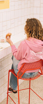 Woman eating pastries in a coffee shop with a pink sweater 