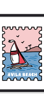 A framed art print featuring a stylized illustration of a sailboat on blue water with a pink sky and the text 'AVILA BEACH' at the bottom, shown against a clean white background.