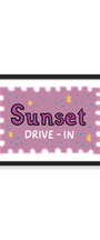 A framed art print featuring a stylized postage stamp design with the words 'Sunset DRIVE - IN' in purple and white lettering on a dusty pink background, with small yellow and blue stars. The print is housed in a simple black frame against a clean white background.