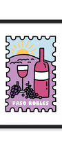 A framed art print featuring a stylized illustration of a wine bottle, wine glass, grapes, and a sun over hills, with the text 'PASO ROBLES' at the bottom. The print is mounted on a white background with a black frame.
