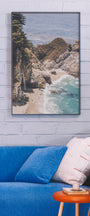 Framed beachscape print on a wall above a blue sofa with a white pillow. Buen Dia art prints San Luis Obispo