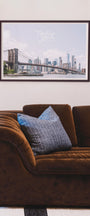 Brown sofa with blue pillows in a room with a framed picture of a city skyline on the wall. Buen Dia art prints San Luis Obispo