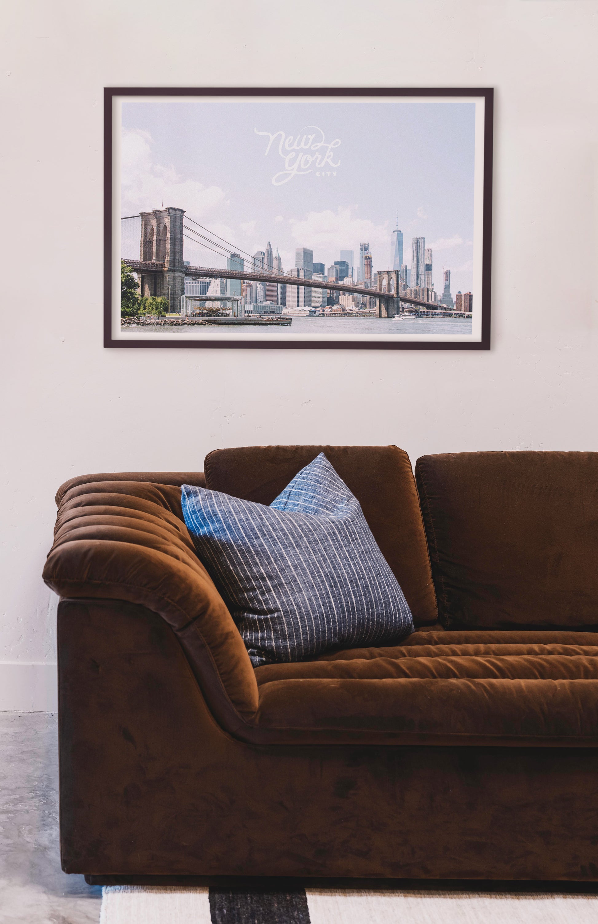 Brown sofa with blue pillows in a room with a framed picture of a city skyline on the wall. Buen Dia art prints San Luis Obispo