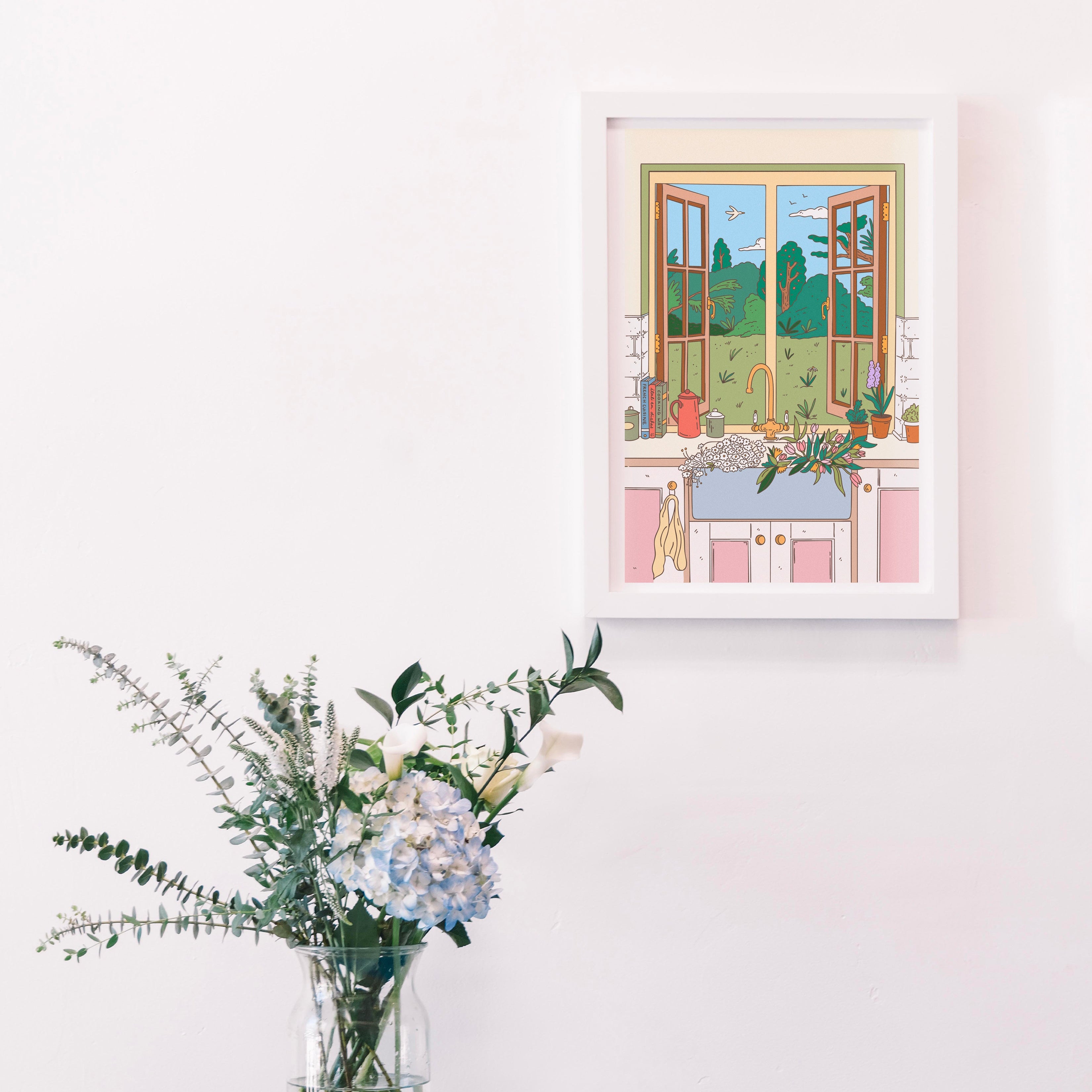 Framed artwork of a window scene above a blue table with flowers and books.