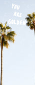 A photographic print featuring two palm trees against a blue sky with the sun setting in the background, and the text 'YOU ARE GOLDEN' overlaid at the top.